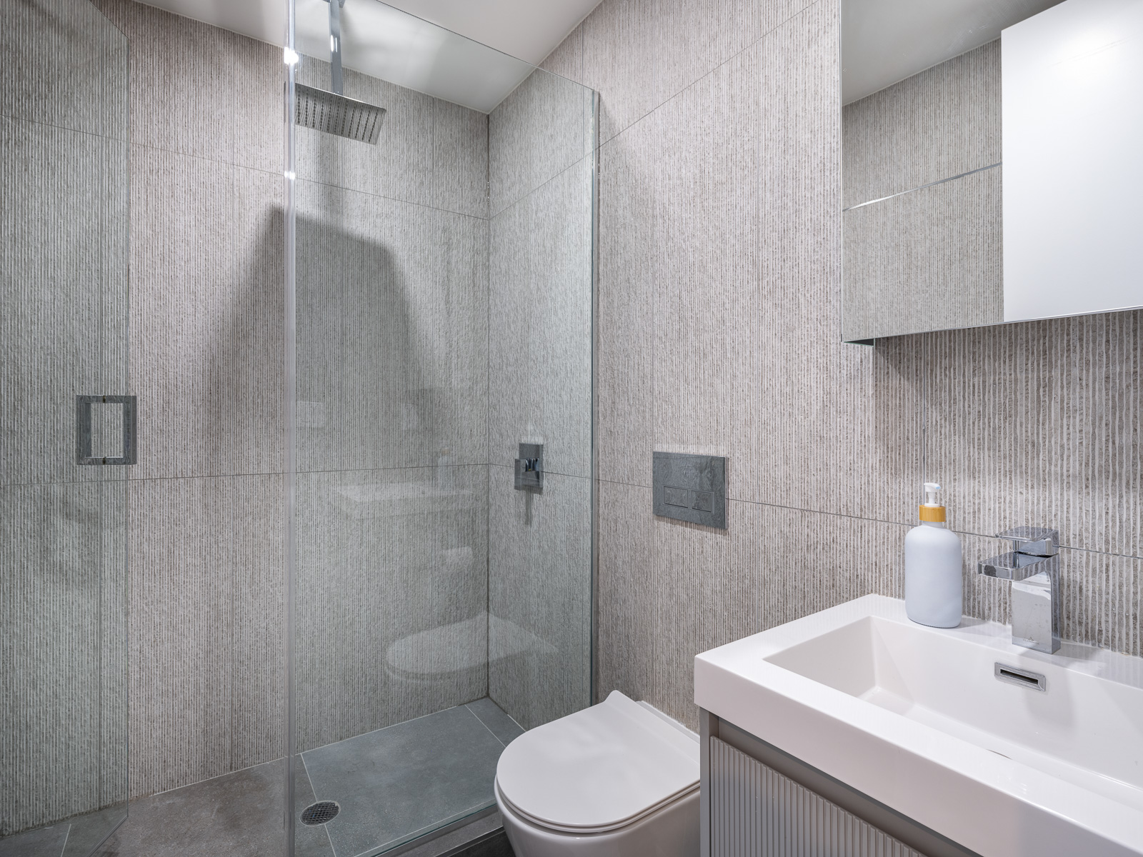 Spa-style bathroom with glass walk-in rain shower and fluted vanity
