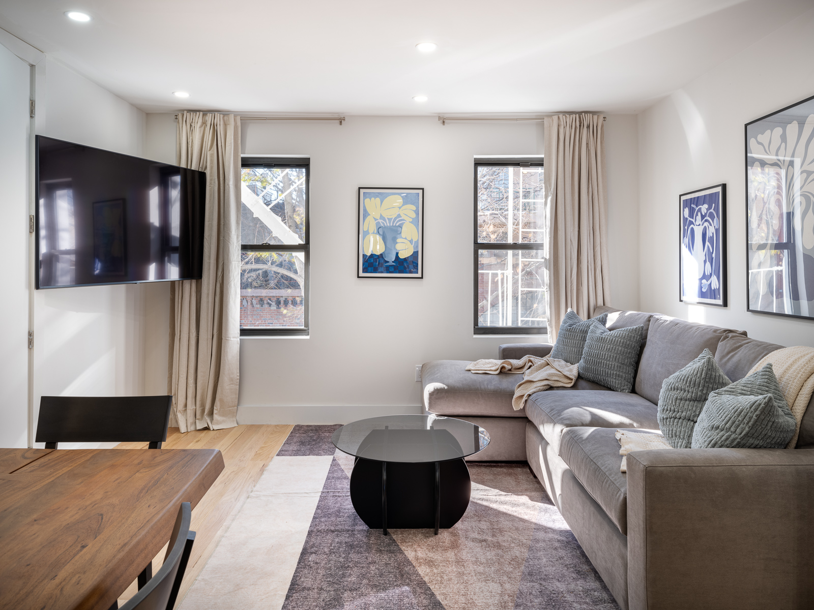 Living room with sectional sofa, mounted TV, and large windows